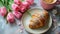 Cup of coffee, croissant and tulips on the table