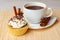 Cup of coffee and cupcake with cream and decorative chocolate sprinkles, cinnamon sticks and anise