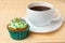 Cup of coffee and cupcake with cream and decorative toppings