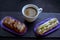 Cup of coffee and delicious eclair cakes - tiramisu and pistachio flavoured