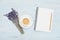 Cup of coffee, empty notebook and lavender flower on blue table top view. Woman working desk. Cozy breakfast. Flat lay style.