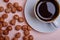 A cup of coffee espresso on a saucer and peeled hazelnuts.