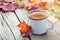 Cup of coffee and fallen maple leaves on wooden boar