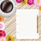 Cup of coffee, flowers, pen and paper on a wooden table. Greeting floral card.