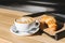 Cup of coffee with french croissant for breakfast on a wooden table in an outdoor cafe