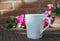 A cup of coffee in the garden with morning light on brickwall and pink flowers background