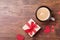 Cup of coffee, gift or present box and red heart on rustic wooden table top view. Holiday breakfast for Valentines day.