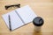 Cup of coffee with glassess and notepad on wooden table