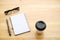 Cup of coffee with glassess and notepad on wooden table