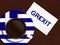 Cup of coffee with greek flag and grexit text lying on wooden de