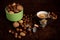 A cup of coffee, a green mug, nuts, almonds, hazelnuts and coffee capsules