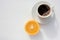 Cup of coffee and half of orange fruit on white background. Top view, copy space. Morning espresso on table. Healthy breakfast.