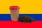 A cup of coffee and a handful of roasted coffee beans against the background of the Colombian flag