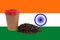 A cup of coffee and a handful of roasted coffee beans against the background of the flag of India