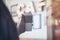 Cup of coffee in the hands of a guy in a cafe against the background of a luminous signboard. Mockup of a cardboard eco mug