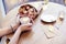 Cup of coffee with heart in woman hands, envelope and flowers on wooden table in cafe. Bokeh on background. Focus on left hand.