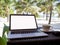 A cup of coffee beside laptop with Coconut tree and sea view, white sand beach background, .Travel plans after retirement of