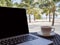 A cup of coffee beside laptop with Coconut tree and sea view, white sand beach background, .Travel plans after retirement of