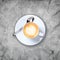 A cup of coffee with latte art on the grey marble backdrop