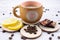 Cup of coffee on a light wooden background. Nearby lies a yellow juicy lemon, dark chocolate with coffee beans scattered in the