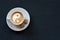 Cup of coffee with milk, cane sugar and yin-yang sign on dark background. Top view. Copy space