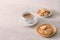 Cup of coffee with milk or cappuccino with cookies on light stone background. Drink with caffeine or cocoa with milk. Coffee break