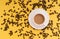 Cup of coffee with milk, coffee beans yellow background, place for text