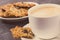 Cup of coffee with milk and fresh baked oatmeal cookies on white plate. Delicious crunchy dessert