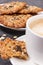 Cup of coffee with milk and homemade oatmeal cookies on white plate. Delicious crunchy dessert