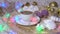 A cup of coffee with milk and marshmallows and garland on wooden salver, other sweets and Christmas decorations around