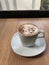 A cup of coffee on a minimal wooden table placed by a large glass window