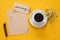 cup of coffee next to blank paper on yellow background