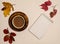 Cup of coffee, notepad, oak leaves, acorns, red maple leaves on a beige background.