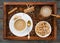 Cup of coffee, nuts in the bowl, coffeepot, cinnamon, anise, sugar, coffee beens on a wooden tray. Flat Lay with no people. View f