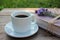 Cup of coffee and old book decorated with lavender flowers and tied with jute twine on wooden table.