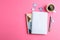 Cup of coffee with petals of flower, copybooks and pen on color background