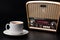 Cup of coffee and radio receiver on black background