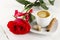 Cup of coffee, red rose, sugar and cinnamon on a white wooden ba