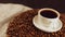 Cup of coffee and saucer on coffee beans. Composition of freshly brewed coffee on roasted beans. Concept of preparation