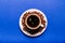 Cup of coffee, saucer with coffee beans and a spoon on a blue background