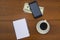 Cup of coffee, smartphone, dollars, notepad and pen on wooden desk