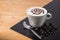 A cup of coffee with spider pattern in a white cup on wooden and blackboard background