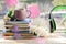 Cup of coffee, a stack of books decorated with hearts, apple flowers on a wooden windowsill