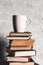 A cup of coffee on of stack of books on grey background. education, study, hobbies, read