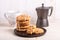 Cup of coffee, stack of oatmeal cookies, coffee maker on white wooden background Homemade bakery