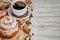 Cup of coffee with steam, coffee beans, chocolate pieces, cinnamon sticks, white and brown sugar, and scoop on burlap background.