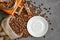 Cup of coffee with steam, coffee beans, chocolate pieces, cinnamon sticks, white and brown sugar, and scoop on burlap background.