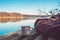 Cup of coffee or tea, backpack of traveller on wooden pier on summer tranquil lake