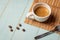 Cup of coffee teaspoon and roasted beans on green background