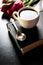 Cup of coffee with tulip and book on black background